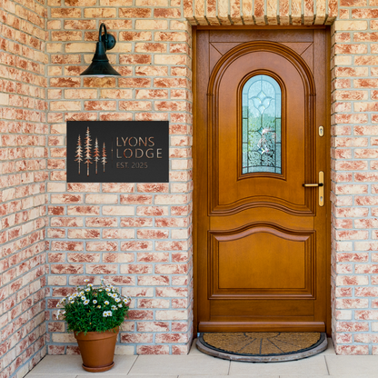 Black custom pine tree lodge metal sign by brick entrance — personalized cabin lodge decor