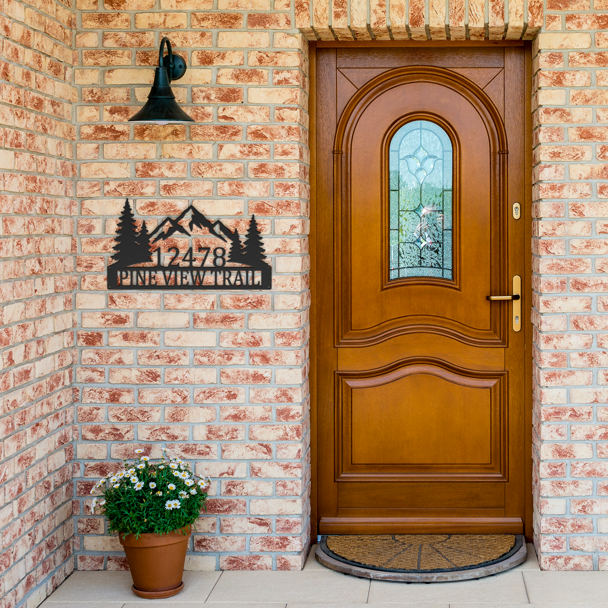 Black custom mountain pine tree address metal sign by brick entrance — personalized house number decor