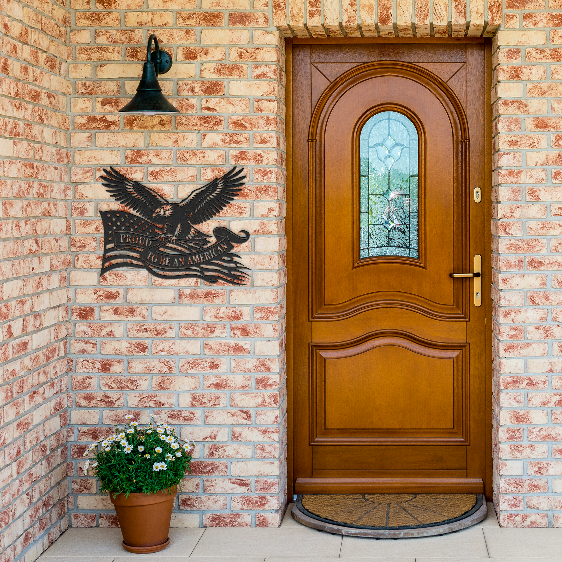 Black Proud to Be an American metal sign by brick entrance — patriotic decor